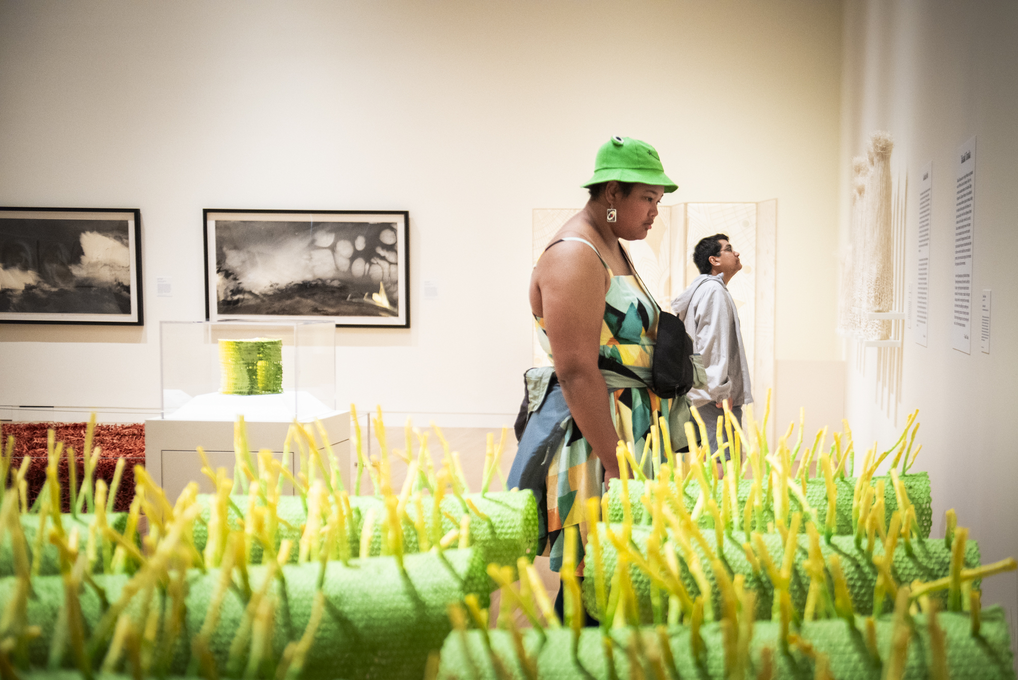 Museum visitors behind a green and yellow paper sculpture